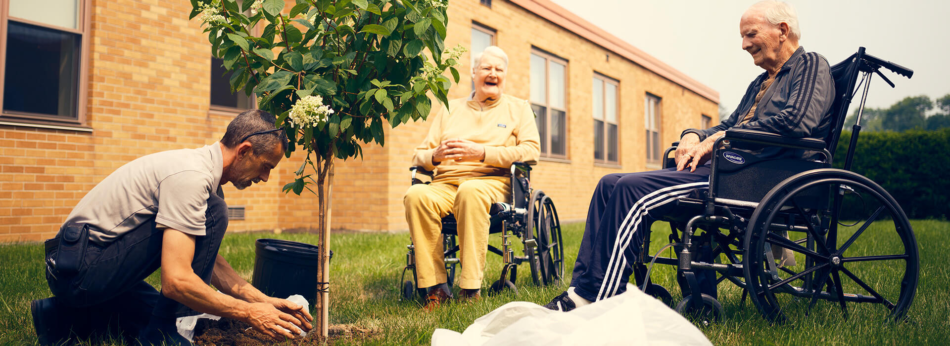Residents enjoying outdoor activity planting a tree.