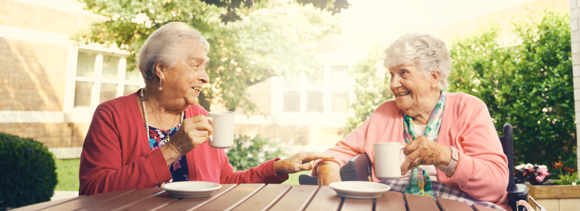 Two elderly women enjoying drinks outdoors.