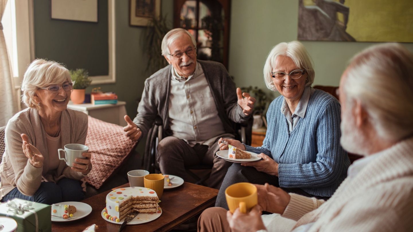 Seniors enjoying cake and coffee in a cozy setting.
