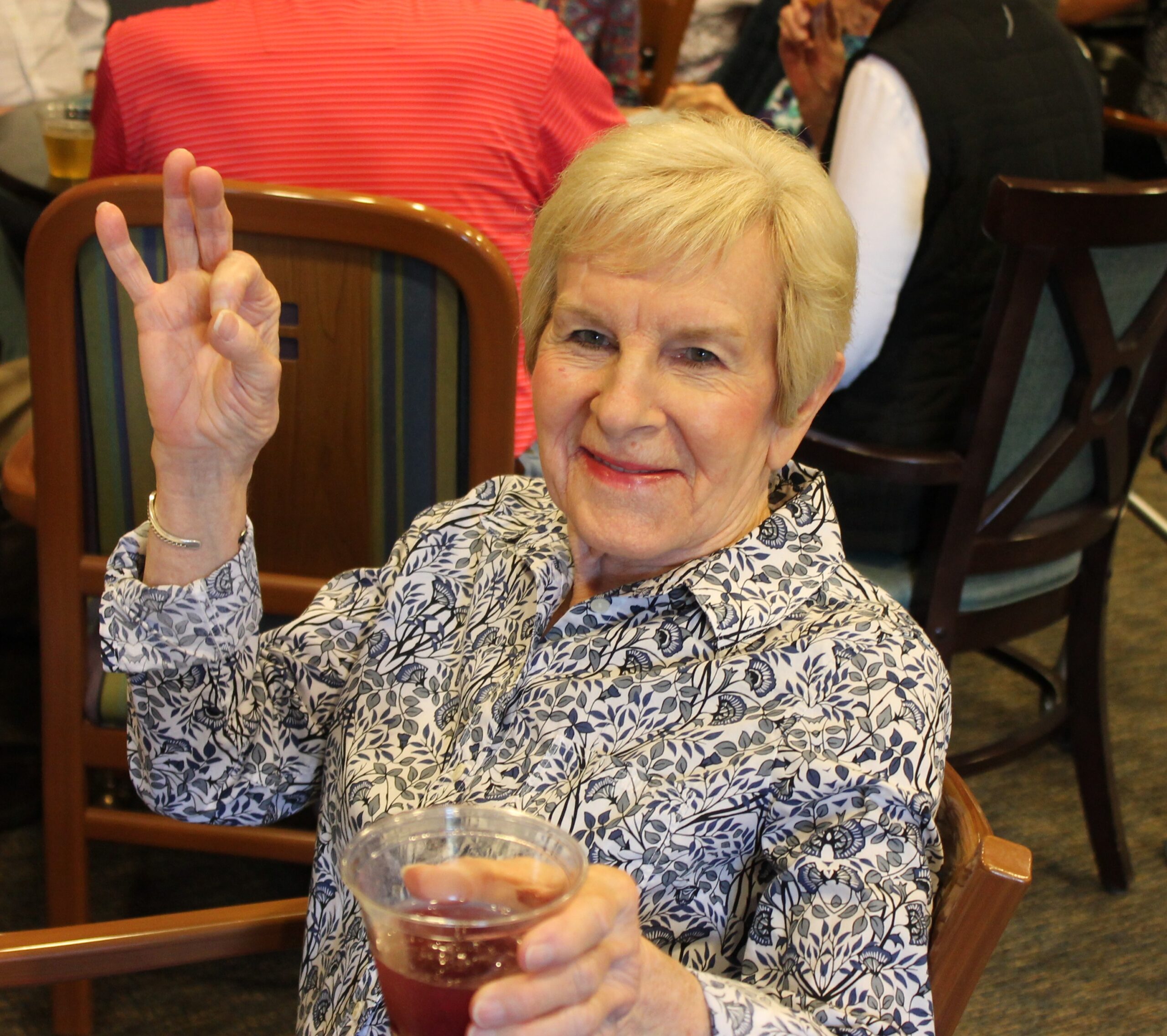 Smiling senior woman with a drink in a social setting.