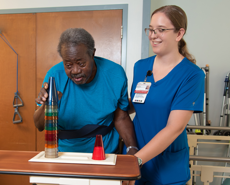 Resident engaging in an activity with staff assistance.