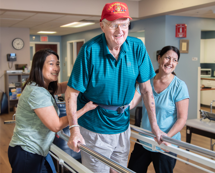 Senior man being assisted with walking by staff