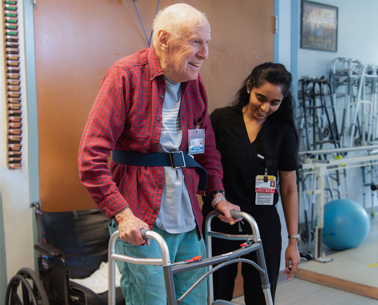 Resident assisted by staff in a rehabilitation setting.