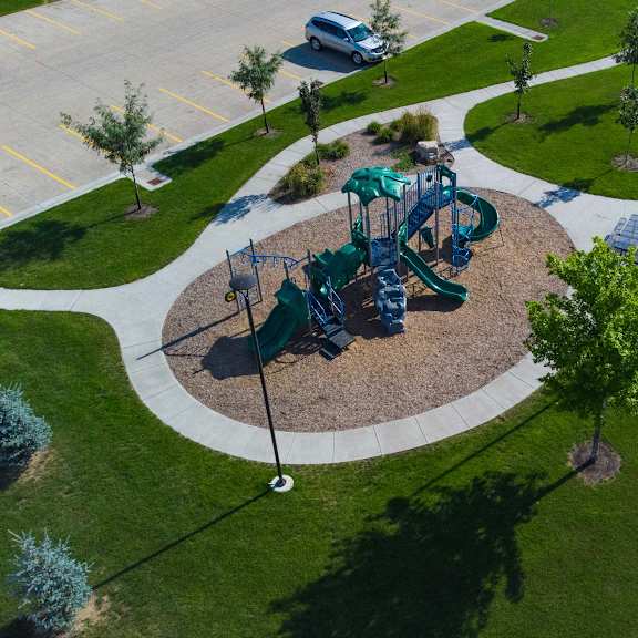 Playground area with grass, trees, and pathways.