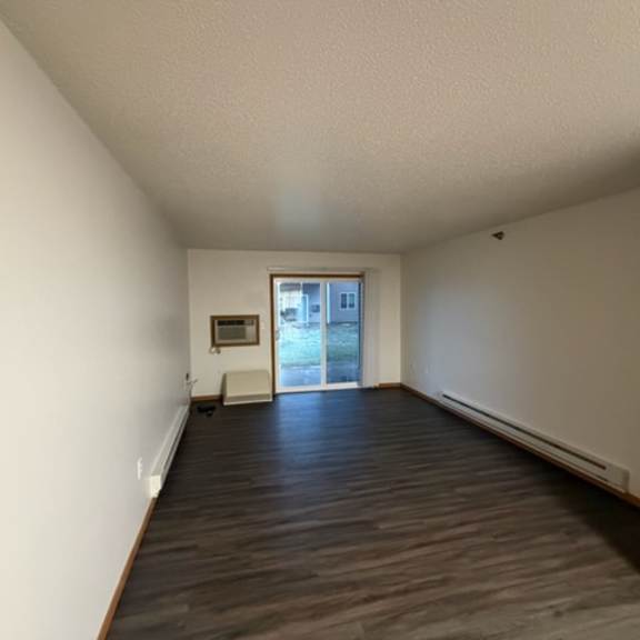 An empty room with wooden flooring and sliding door