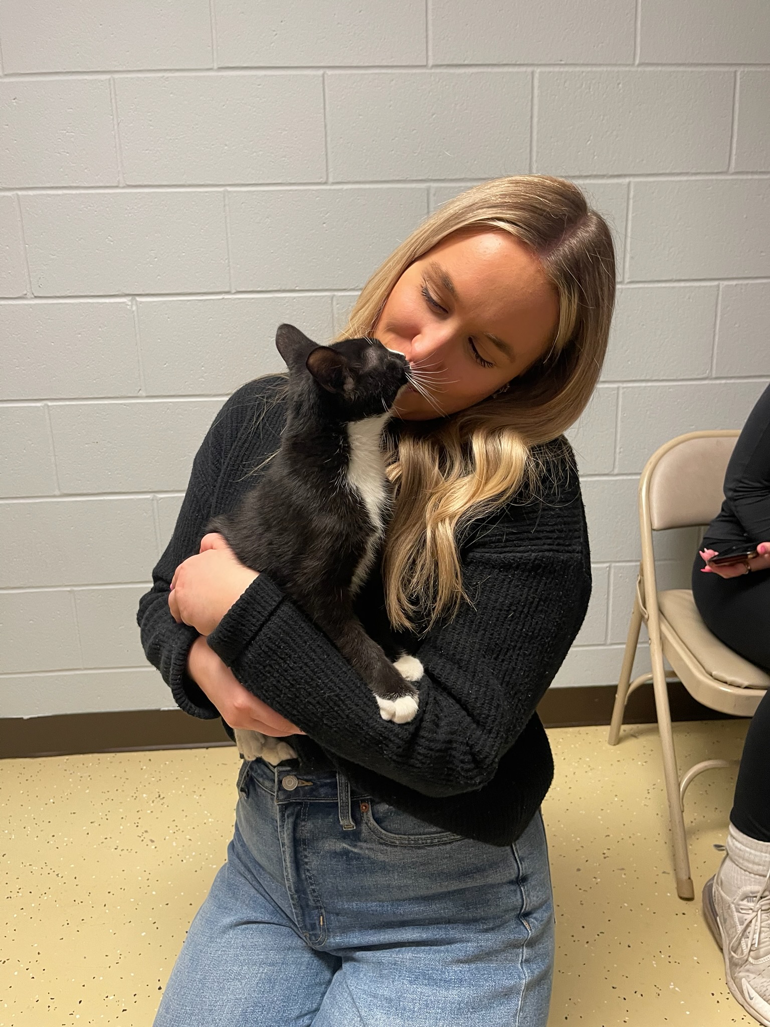 Woman holding a black and white cat indoors.