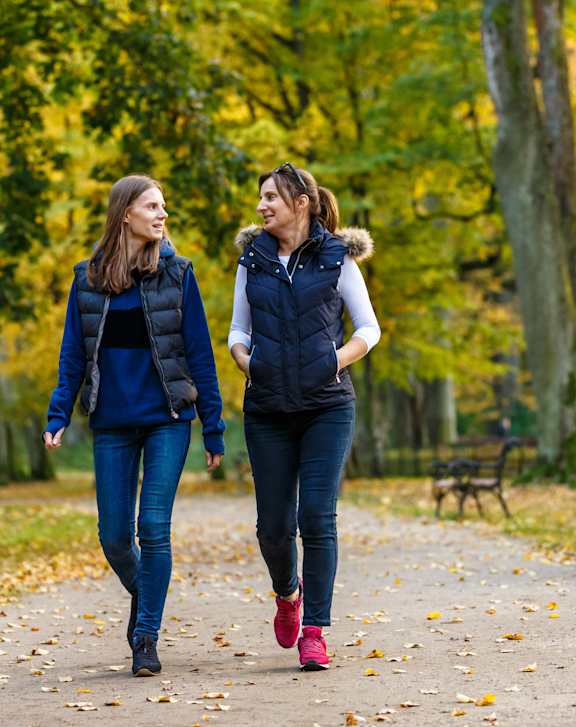 Two women walking in a park during autumn