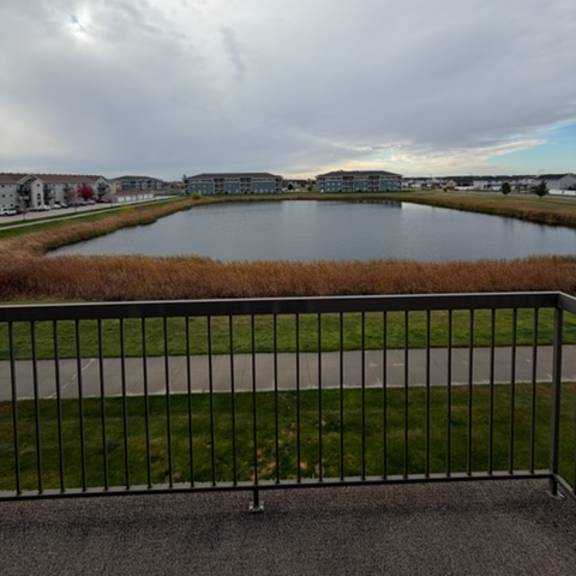 View of a pond and nearby buildings from a balcony.
