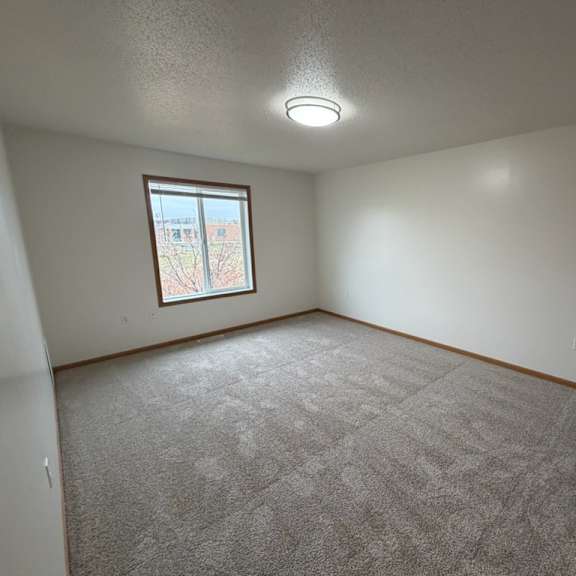 Empty resident room with carpet and window.