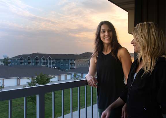 Two women enjoying the balcony view at sunset.