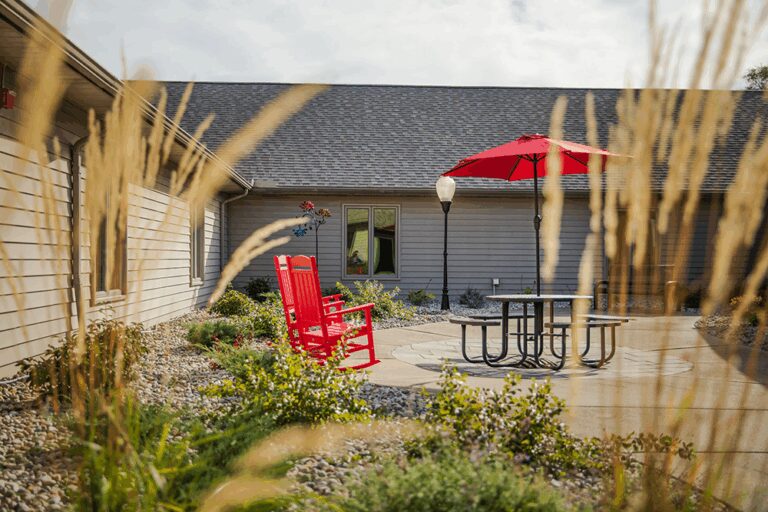 Outdoor seating area with a red rocking chair and umbrella