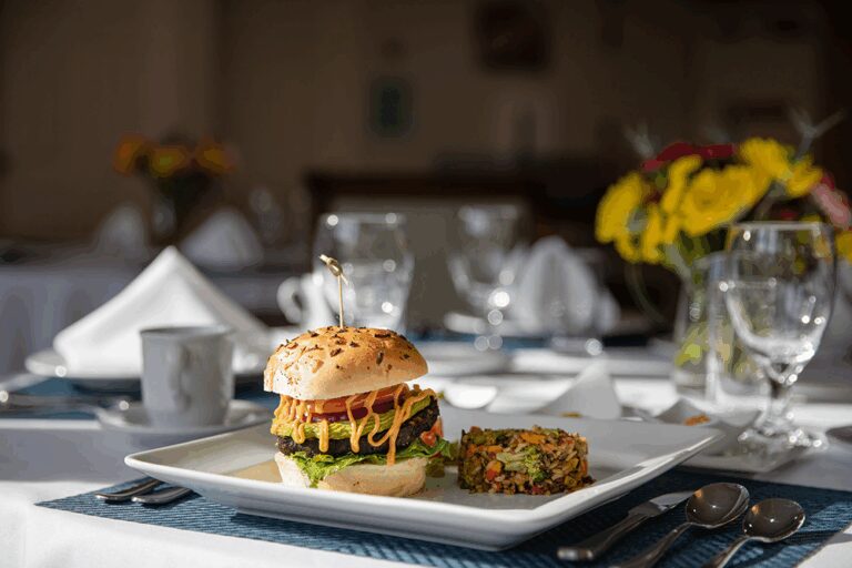 A gourmet burger and side dish on a dining table.