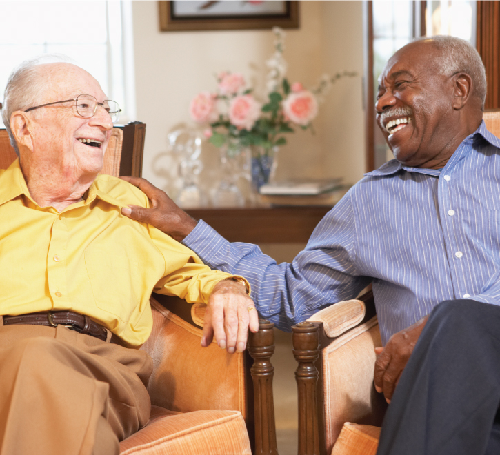 Two elderly men laughing together in a common area
