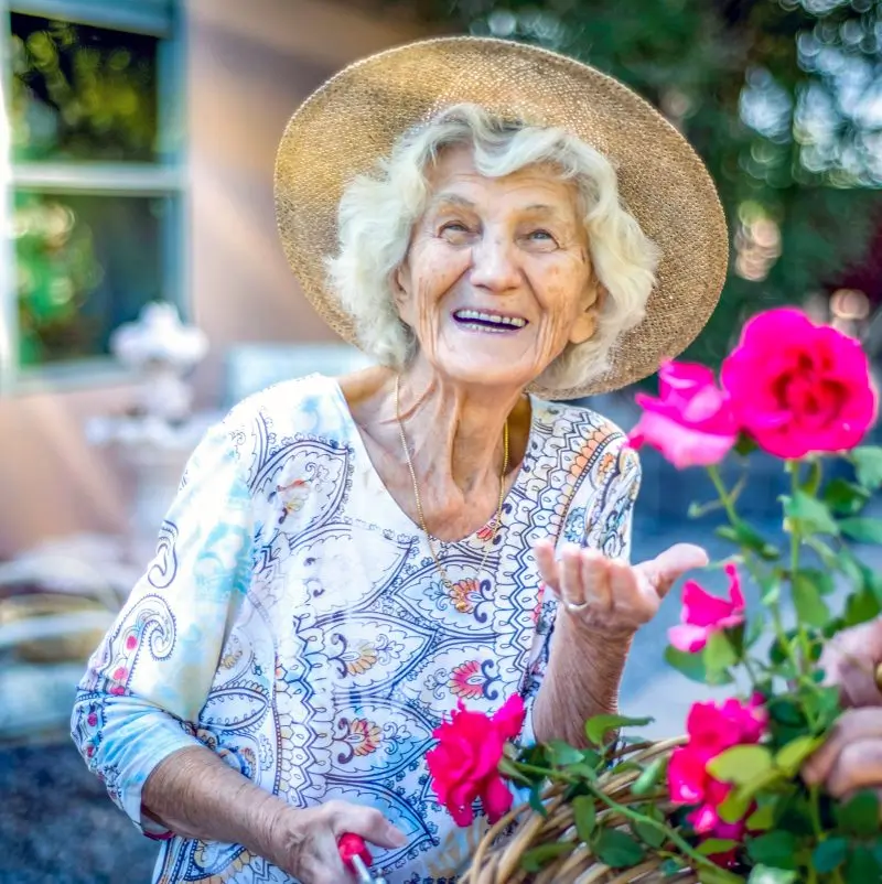 Smiling elderly woman with flowers outdoors