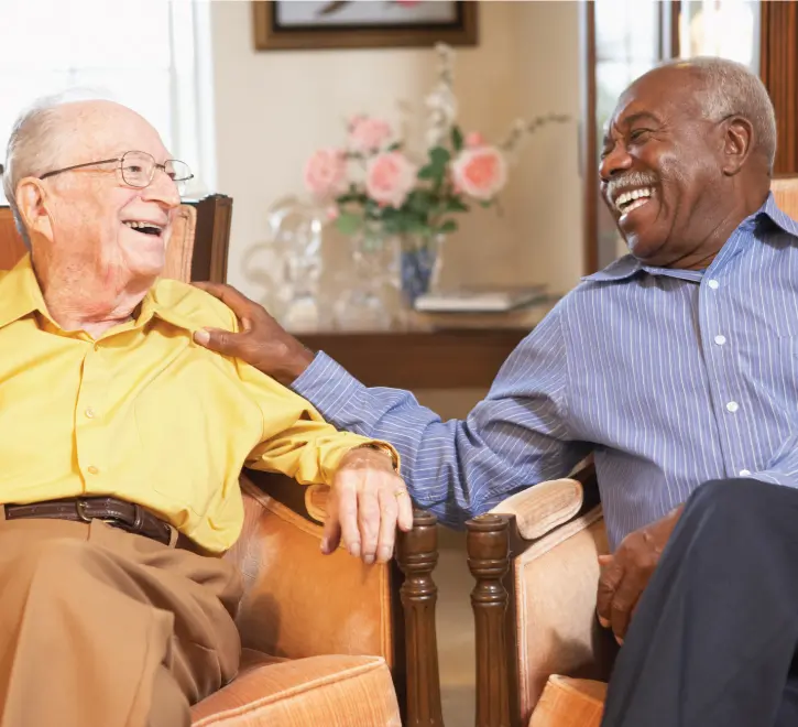 Two senior men laughing together in a common area
