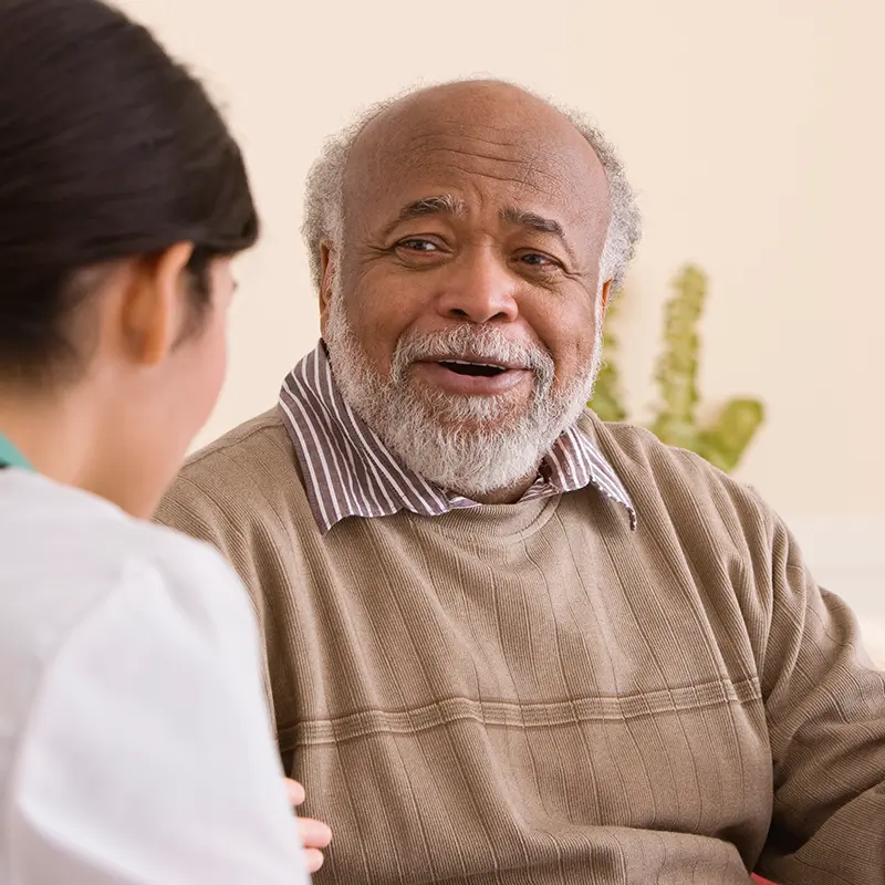 Elderly man conversing with a caregiver.