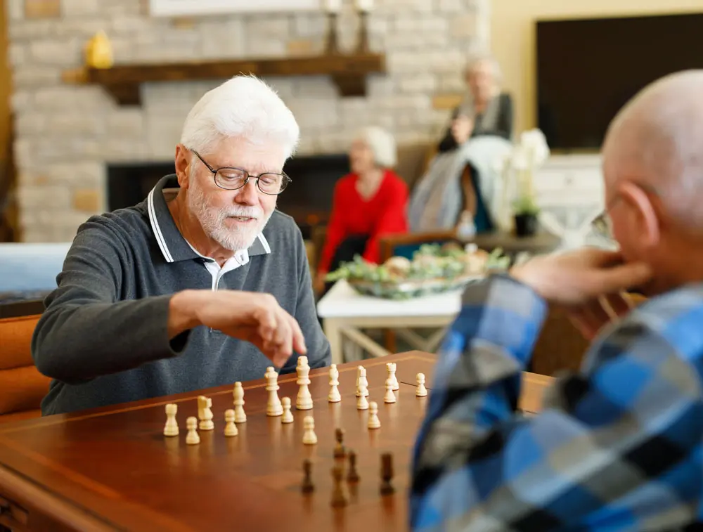 Two seniors playing chess in a common area.
