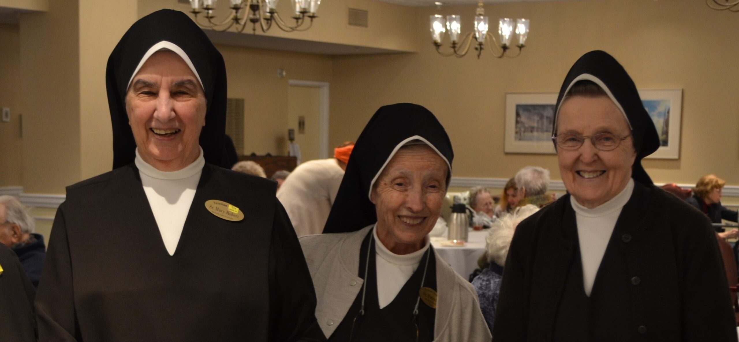 Three smiling nuns in a common area of the facility.
