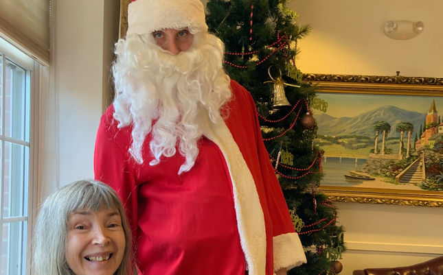 Resident with Santa Claus in a festive setting.