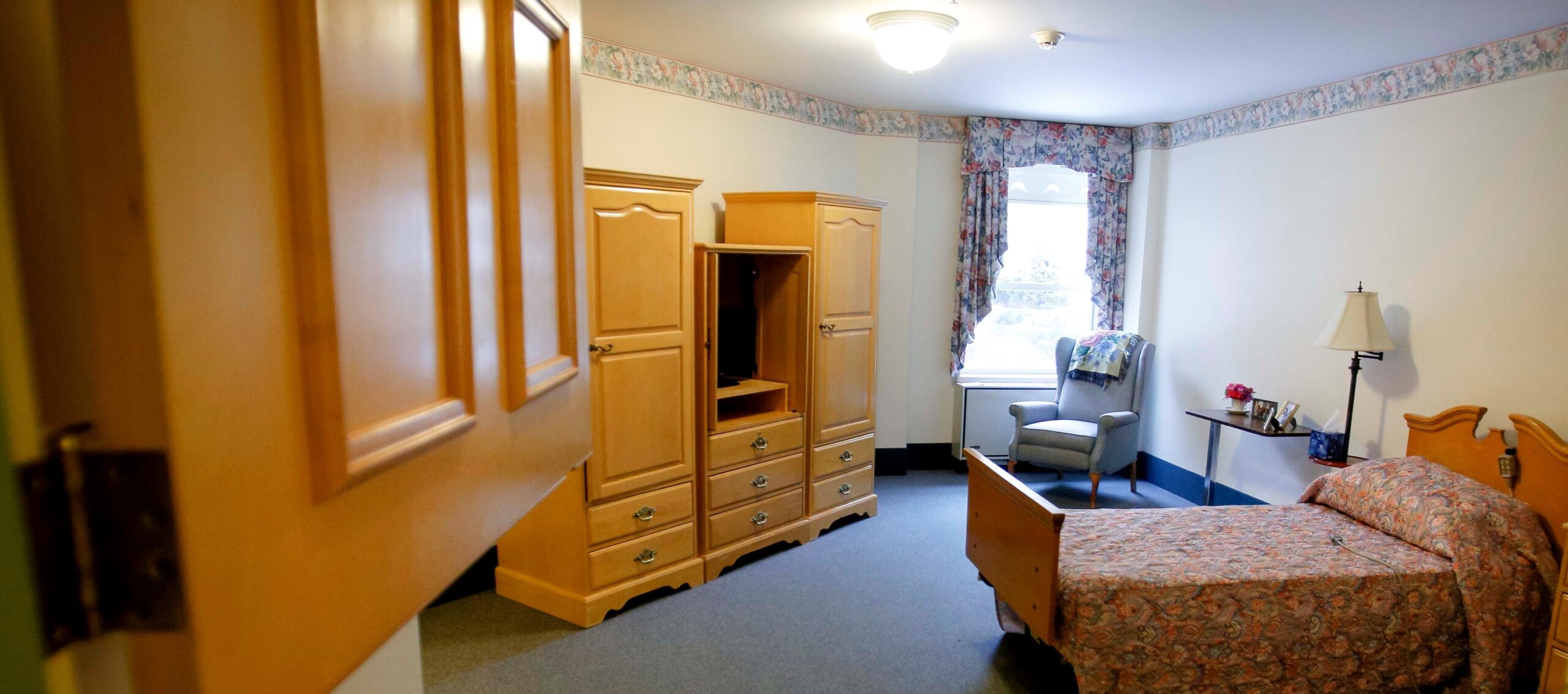 Cozy resident room with furniture and floral curtains.