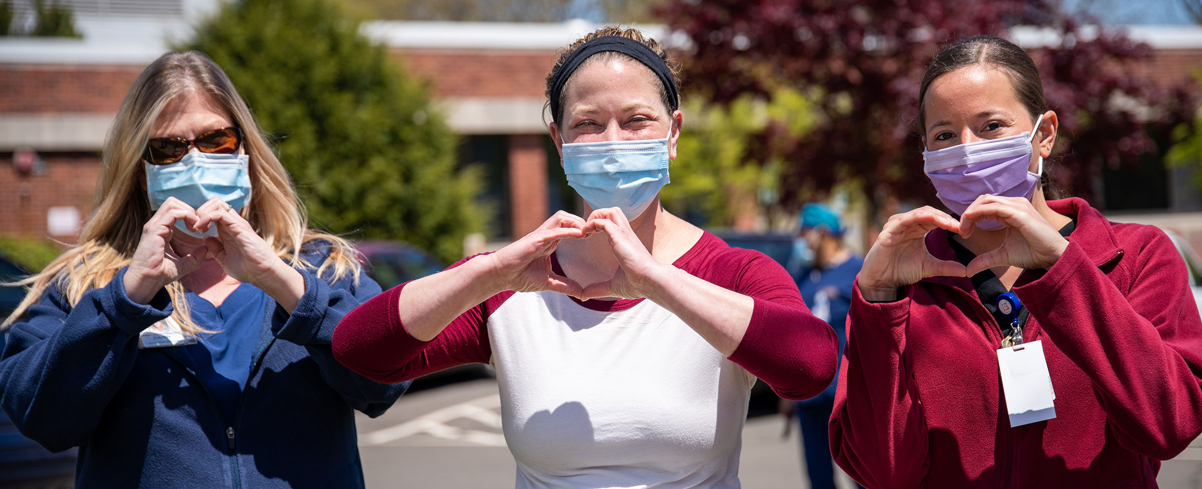Staff members showing heart signs outdoors