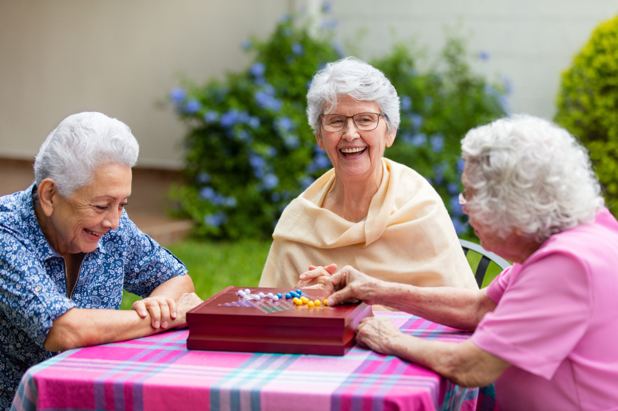 Three elderly women playing a game outdoors