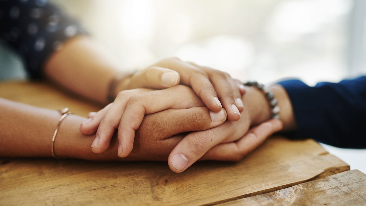 Hands of two people together on a table