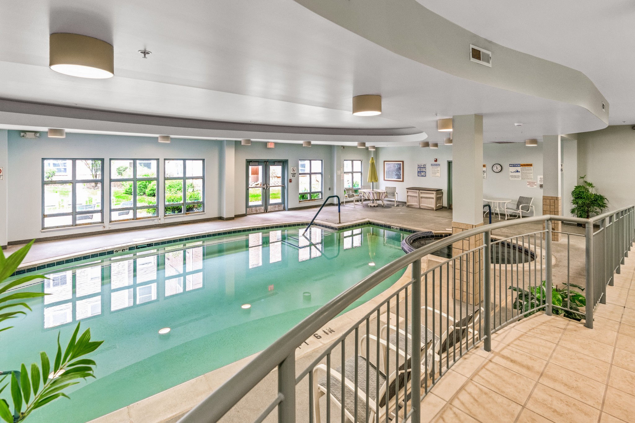 Indoor swimming pool area with seating and natural light