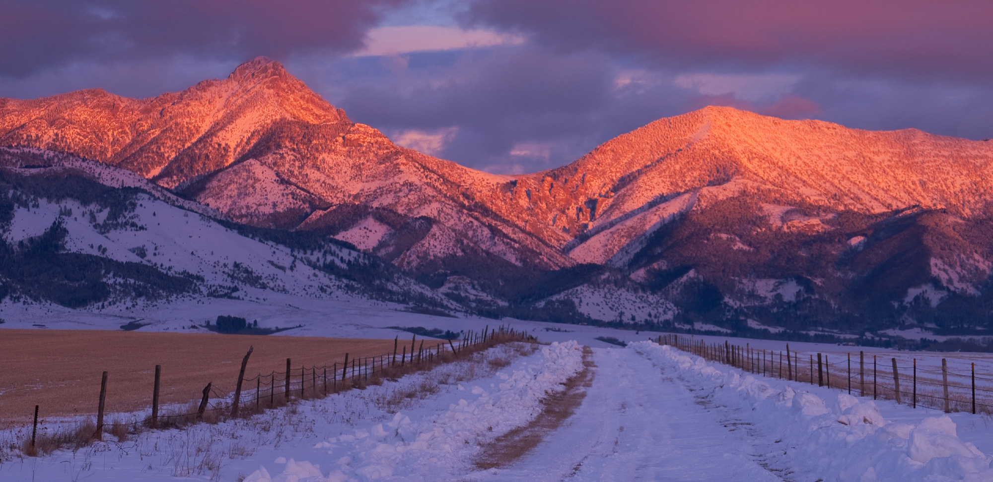 Mountain landscape at sunset with snow and fields