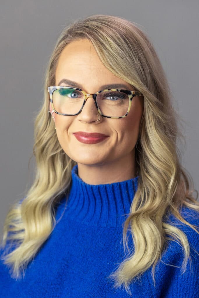 Smiling woman with glasses in a blue sweater