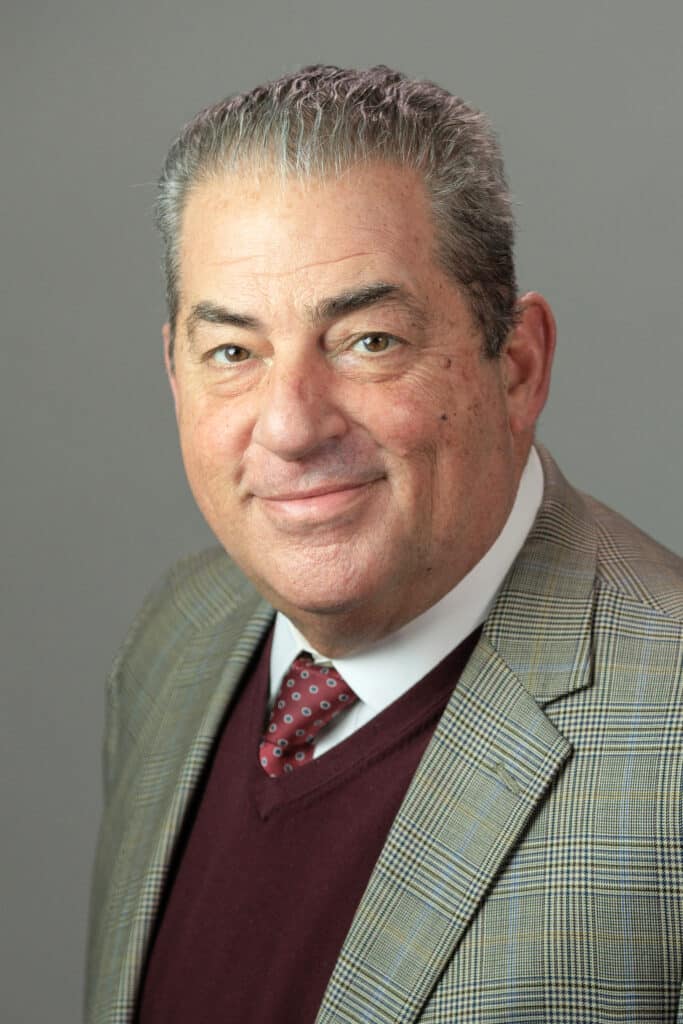 A man in a professional suit smiling at the camera