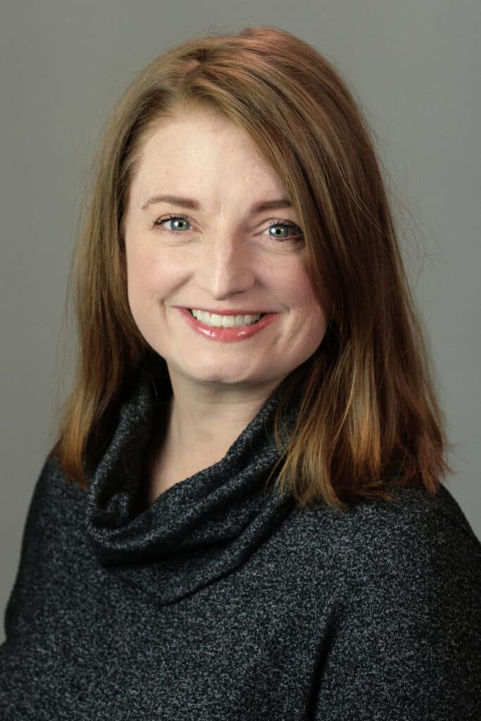 A smiling woman with medium-length hair in a black sweater