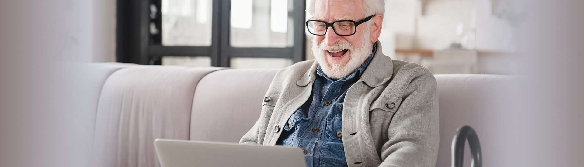 Senior man happily using a laptop in a common area