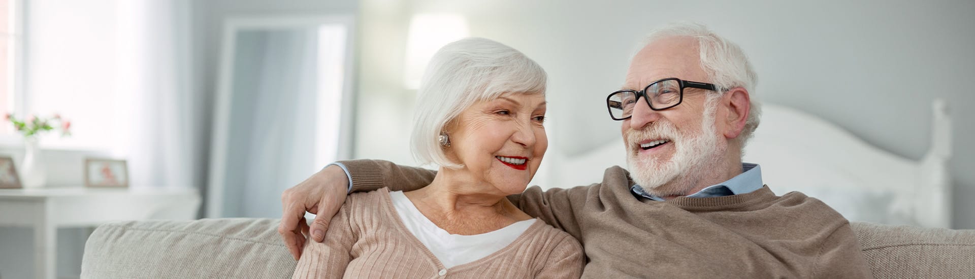 Elderly couple smiling together in a cozy living room