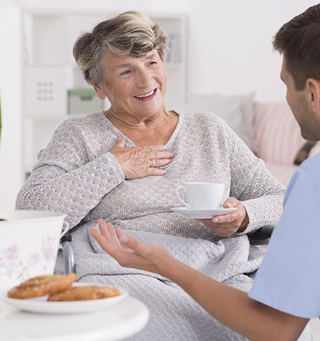 Resident enjoying tea with staff in cozy setting