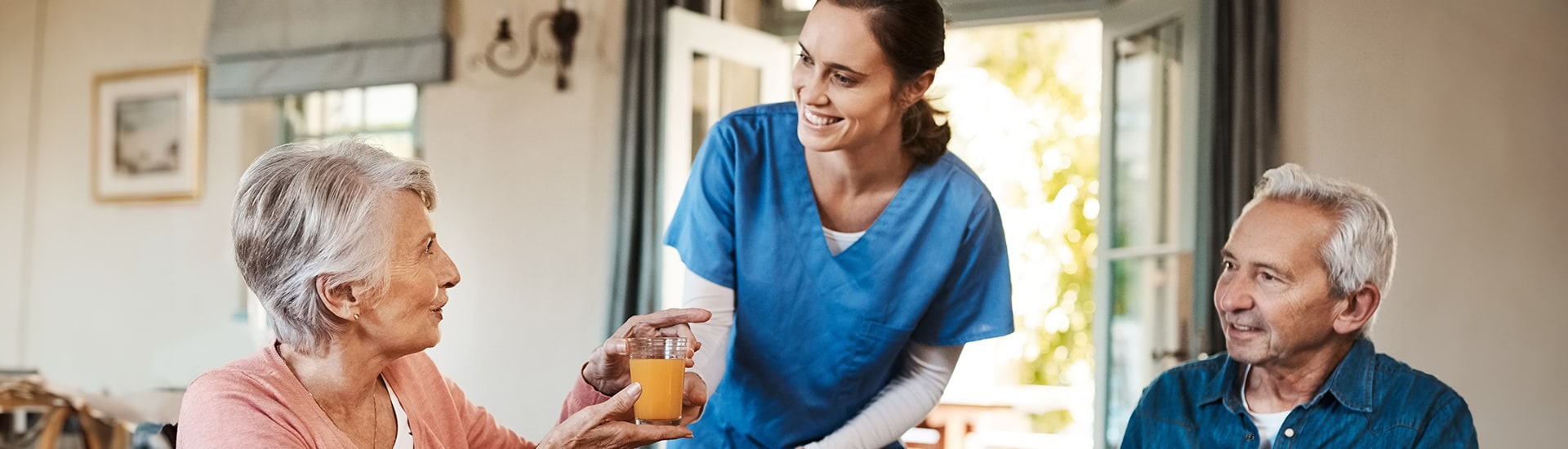 Staff member serving juice to smiling residents