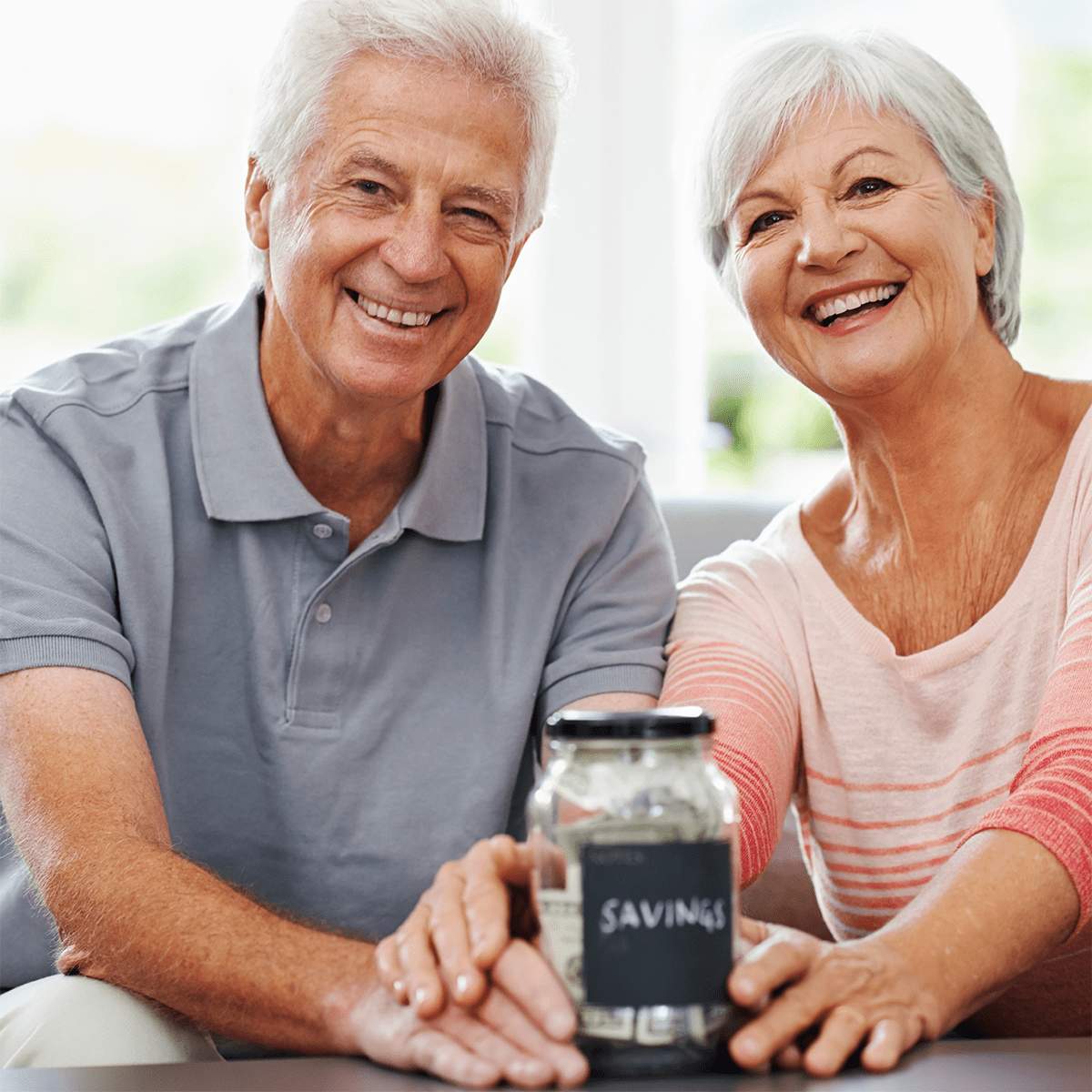 Two seniors smiling with a savings jar between them