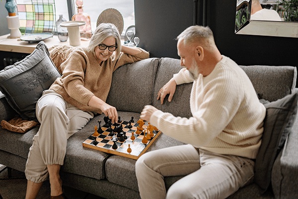Two residents enjoying a game of chess in a cozy living room