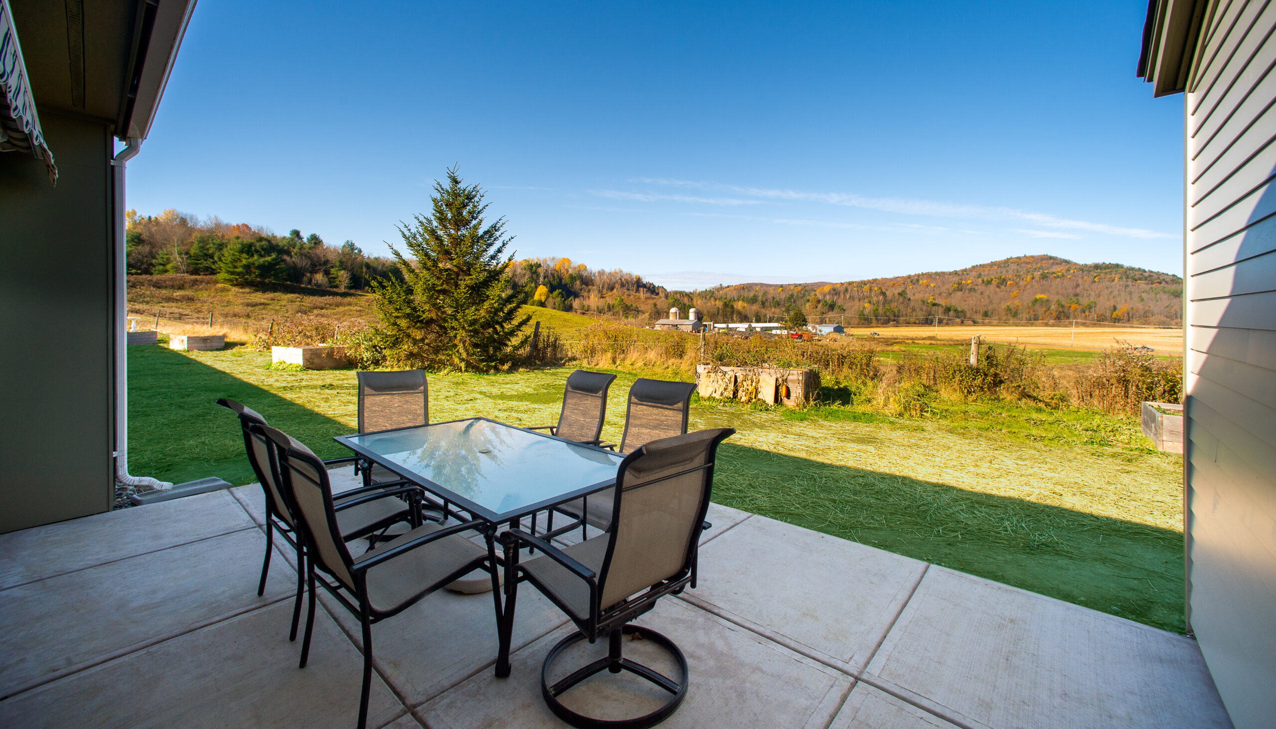 Outdoor patio area with a table and chairs overlooking a field
