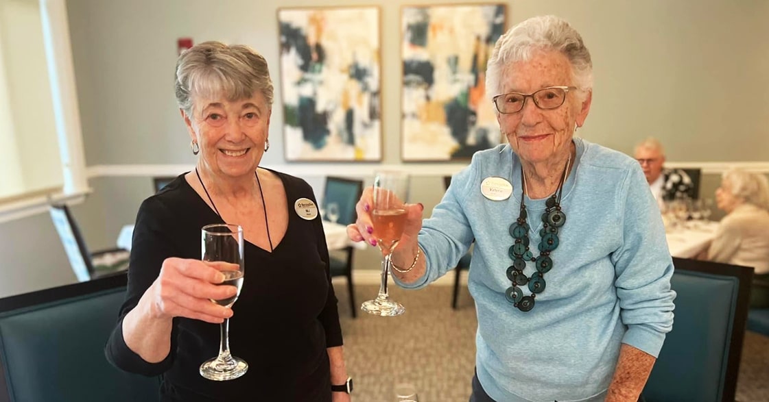Two residents toasting with drinks during an event