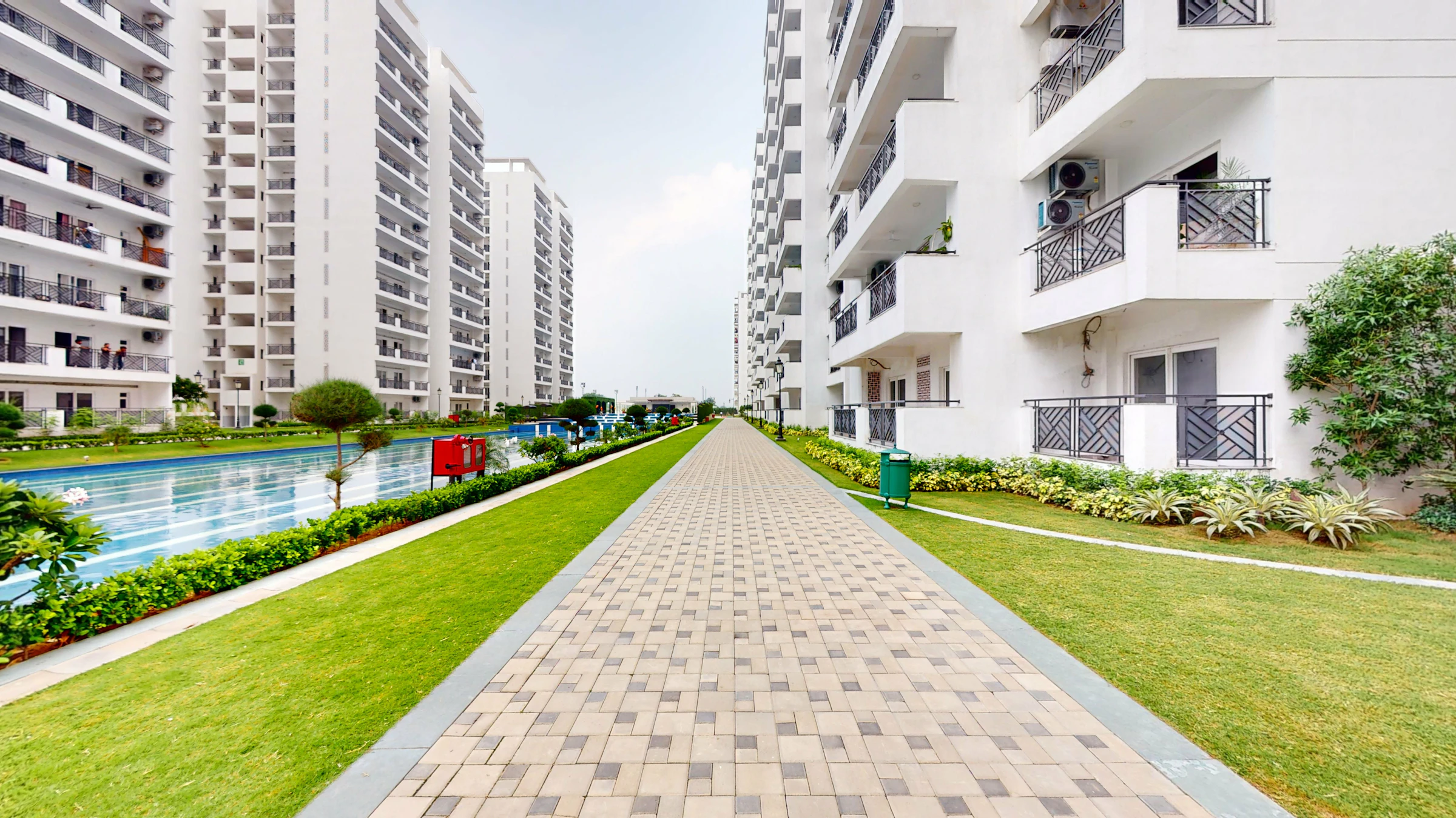 Pathway with greenery and buildings near a pool
