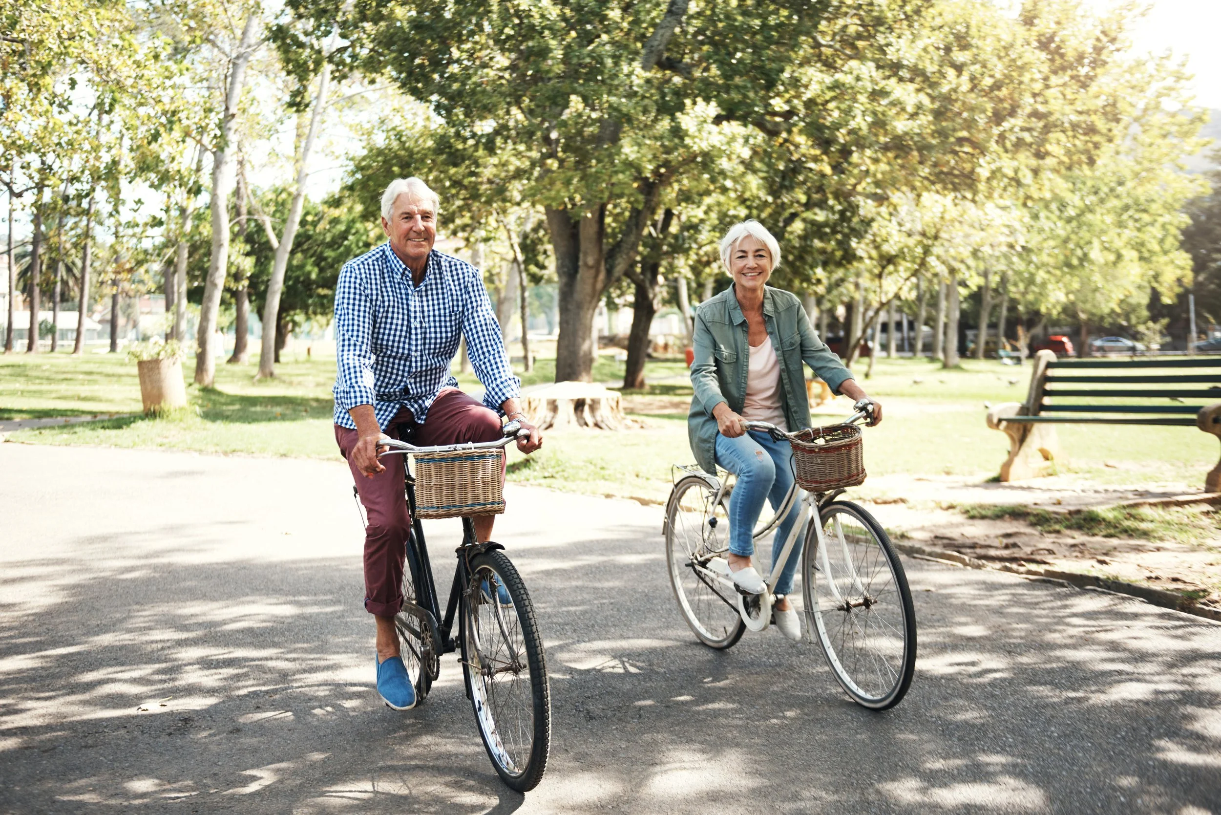 Two seniors riding bicycles in a park