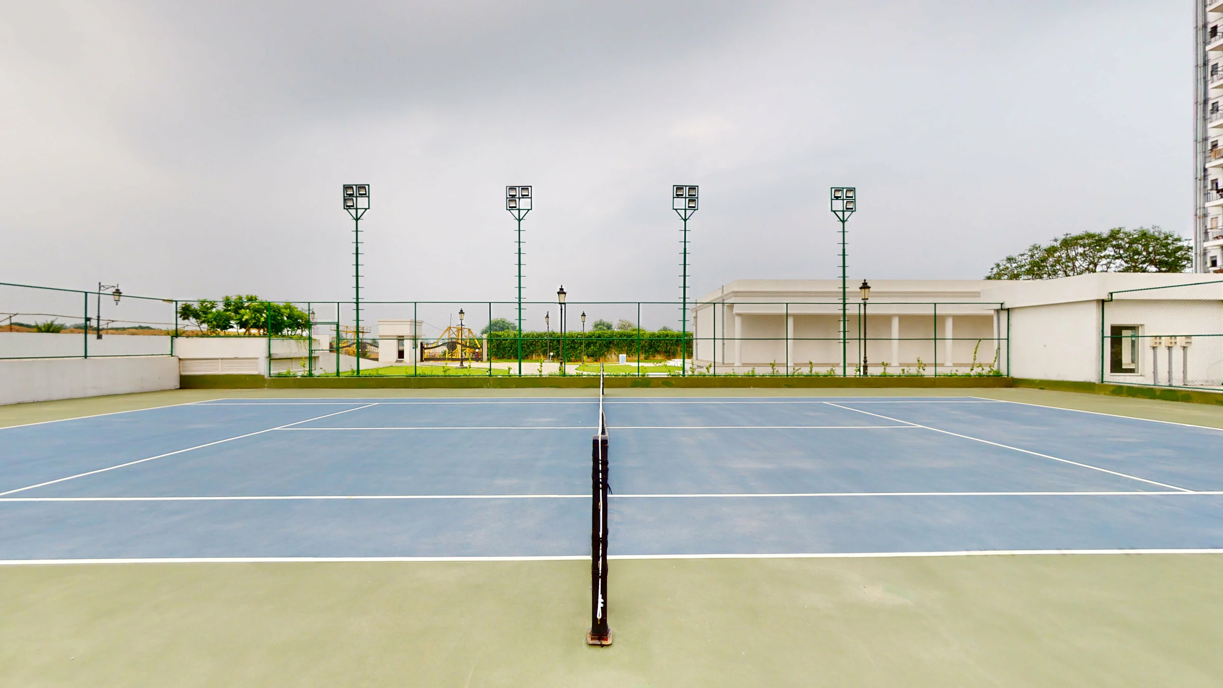 Outdoor tennis court with blue surface and surrounding greenery