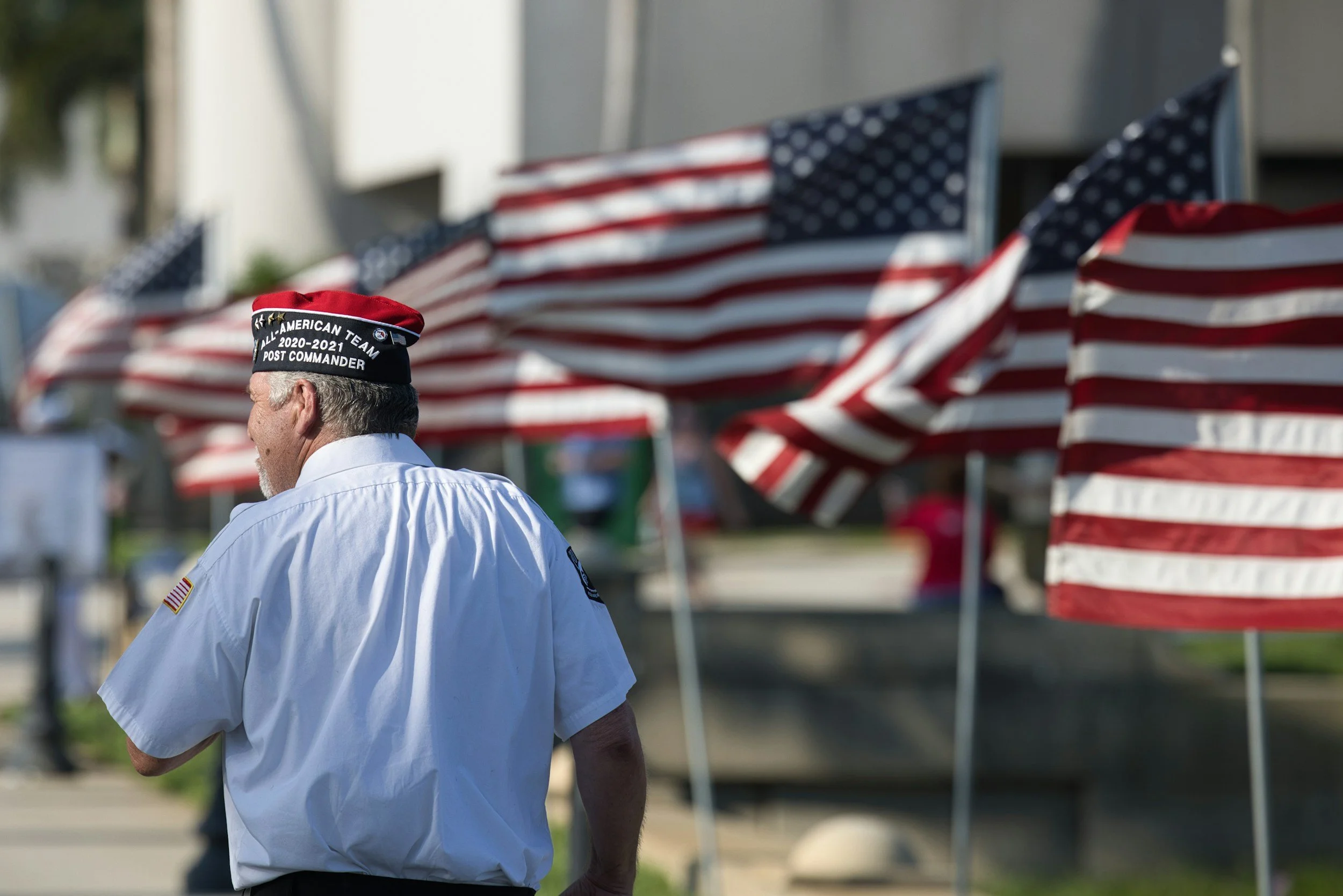 A veteran walking past American flags on a sunny day