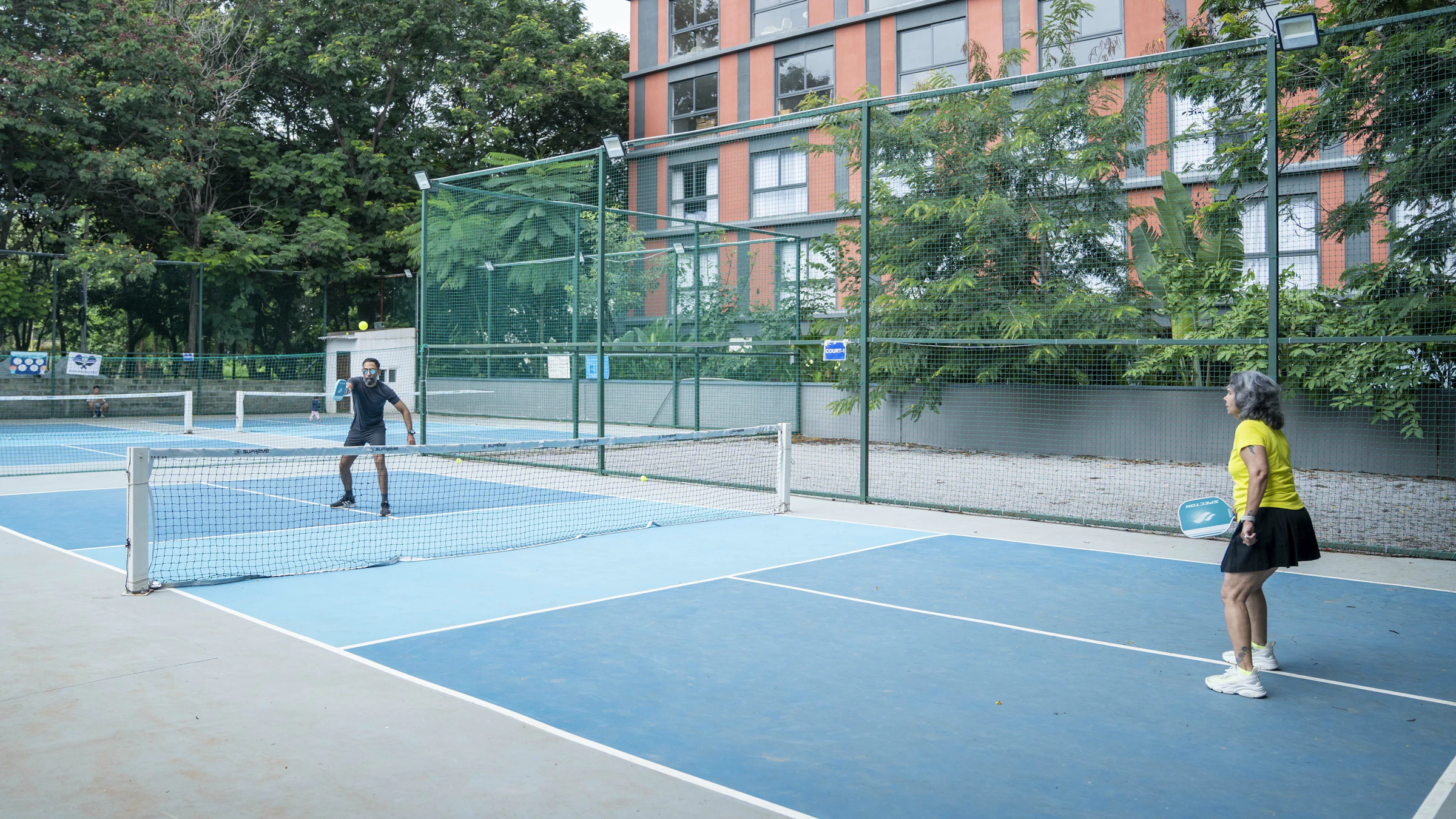 Residents playing tennis in a sunny outdoor court