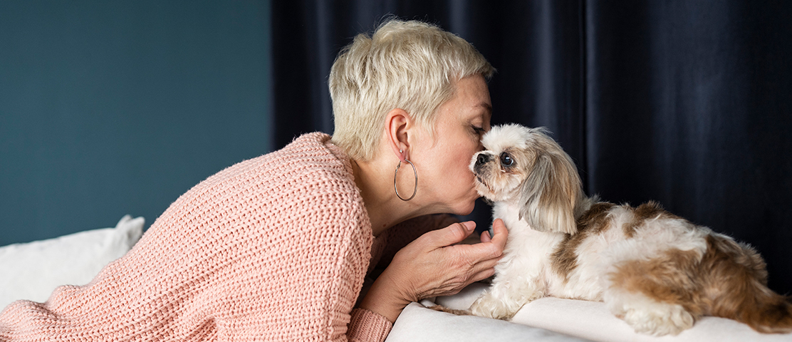 A woman sharing a loving moment with a small dog indoors