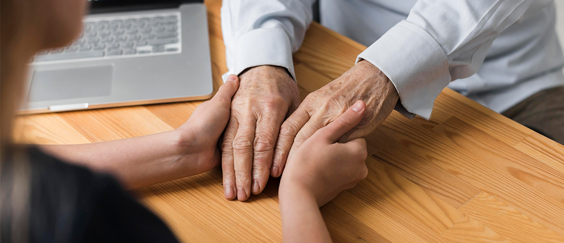 Close-up of hands between a caregiver and a senior