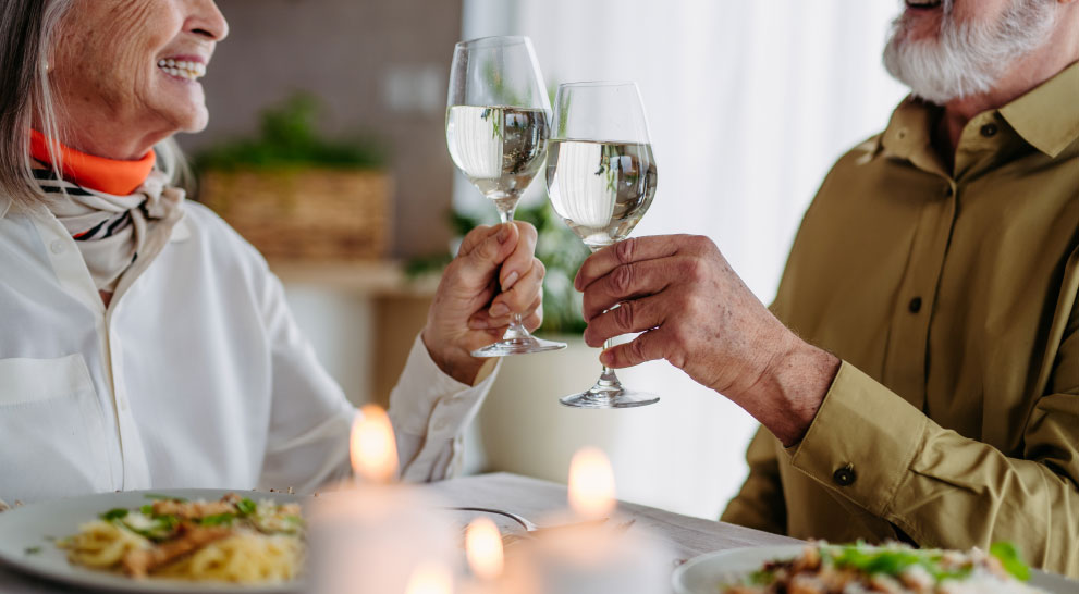 Two residents toasting with glasses in a dining setting