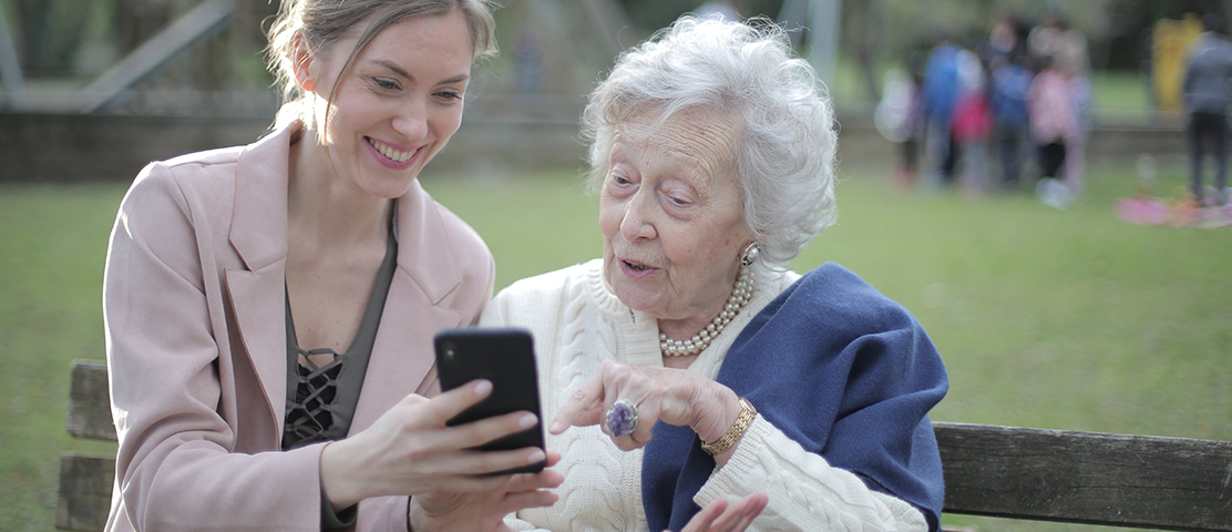 A staff member and resident laughing together in a park.