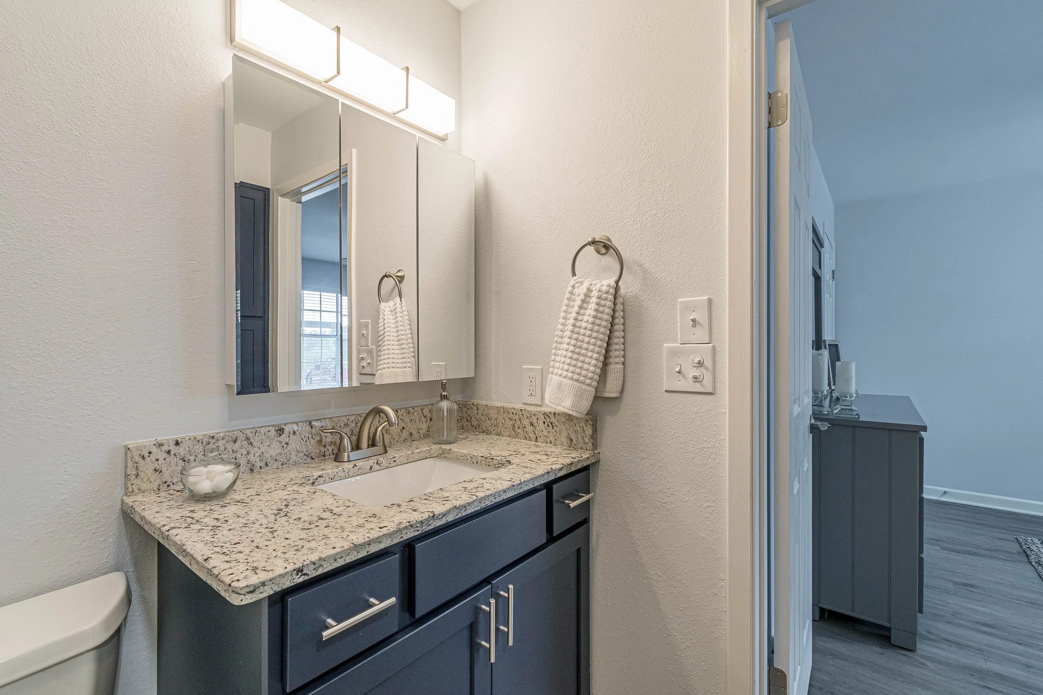 A modern bathroom with granite countertop and mirror